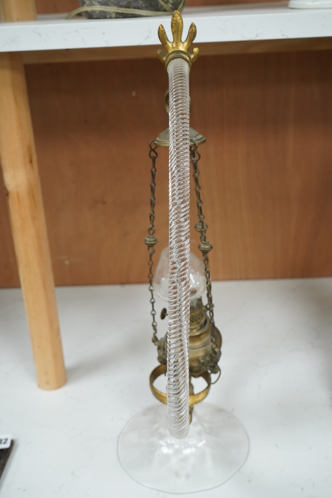A Victorian glass frame with a central brass hanging oil lamp. 48cm high